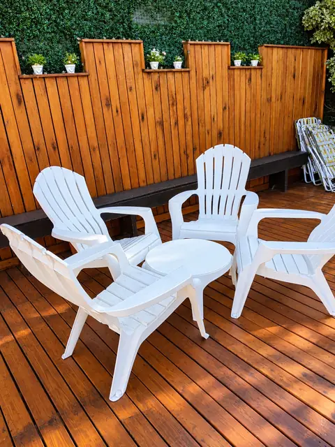 Deck de madera con sillas blancas y mesa ratona