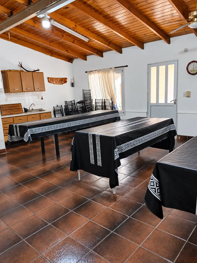 Salón con varias mesas largas vestidas, listo para un evento